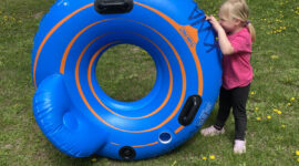 Girl showcasing blue, circular rental tube with backrest at Kickapoo Wild Adventures